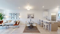 This well-designed multi-level home spans three floors, offering a thoughtful layout that balances functionality with modern aesthetics. The interior is characterized by a clean, bright palette of white walls, light hardwood-style flooring, and recessed lighting that creates a welcoming atmosphere throughout.

The main living level features an open-concept kitchen, dining, and living area. The kitchen is equipped with white shaker cabinetry, white quartz countertops, stainless steel appliances, a subway tile backsplash, and a peninsula with bar seating — ideal for casual dining or entertaining. The adjoining living and dining space flows seamlessly, with a sliding glass door opening to a private balcony that brings in abundant natural light and outdoor views of the surrounding neighborhood.

Hallways connect the floors via carpeted stairs, with bathrooms conveniently distributed across all levels. The five bathrooms are finished with light wood-tone cabinetry, white countertops, and clean modern fixtures. The spacious primary bedroom features soft carpeting, neutral tones, and generous wall space. A dedicated office with large windows offers a bright, functional workspace. The ground floor provides additional utility space, completing this versatile and well-appointed home.