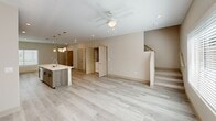 Located in Azalea Park in Naples, FL, this thoughtfully designed two-story home offers three bedrooms and three bathrooms across two well-proportioned floors. The main level features an open-concept layout where the kitchen flows seamlessly into the living area, creating a bright and airy atmosphere enhanced by recessed lighting and a ceiling fan. The kitchen is a standout feature, showcasing warm wood-toned cabinetry that extends to the ceiling, a large center island with a white quartz countertop and undermount sink, stylish pendant lighting, and a full suite of stainless steel appliances. Light luxury vinyl plank flooring runs throughout the main level, adding to the clean, contemporary feel. A laundry area and additional storage closets are conveniently located on this floor, along with access to the carpeted staircase leading to the upper level. Upstairs, three carpeted bedrooms provide comfortable retreats, including a primary bedroom featuring dual closets. The bathrooms are finished with wood-toned vanities, white quartz countertops, and neutral tile work, with one bathroom offering a double-sink vanity and another featuring a full soaking tub and shower combination. The home's consistent use of neutral tones and modern finishes creates a cohesive, move-in-ready aesthetic throughout.