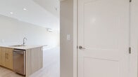 Located on the sixth floor at 2673 Trinity St in Abbotsford, BC, this well-appointed one-bedroom, one-bathroom unit offers a thoughtfully designed open-concept layout. Light wood laminate flooring flows throughout the living spaces, lending a warm and contemporary feel.

The combined kitchen and living area forms the heart of the unit. The kitchen is outfitted with two-tone cabinetry — crisp white upper cabinets paired with natural wood lower cabinets — complemented by white quartz countertops, a large island with an undermount sink, stainless steel appliances including a refrigerator and range, and recessed pot lighting overhead.

The living area is bright and airy, bathed in natural light from large windows that frame views of the surrounding neighbourhood and greenery. Sliding glass doors lead directly to a private balcony, extending the living space outdoors. A wall-mounted ductless mini-split unit provides efficient climate control throughout.

The bedroom is a composed, comfortable space featuring a large window with outdoor views and a baseboard heater. Neutral warm-toned walls carry through the unit, creating a cohesive and calming palette.

The bathroom is finished with dark tile flooring, a wood-toned vanity, a glass-enclosed shower, and a round mirror, combining modern and natural design elements for a polished look.