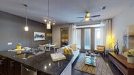 This single-story, two-bedroom, two-bathroom residence in Houston, TX offers a thoughtfully designed open-concept layout with contemporary finishes throughout. The entryway, accented by dark hardwood flooring, leads directly into the kitchen and living areas, establishing a seamless flow across the main living spaces.

The kitchen is a standout feature, showcasing rich dark cabinetry, granite countertops with an undermount double sink, a green subway tile backsplash, stainless steel appliances, and track lighting overhead. A generous island provides additional workspace and serves as a natural boundary between the kitchen and the combined living and dining area.

The living room is anchored by large French doors that invite natural light and offer outdoor access, complemented by a ceiling fan, track lighting, and dark hardwood floors. A compact dining nook sits adjacent, completing the open entertaining space.

Both bedrooms are carpeted and well-proportioned, with ceiling fans and large windows. The primary bedroom features a bold accent wall and ample natural light. Its en-suite bathroom offers a dual-sink vanity with granite countertops, a soaking tub, and a separate walk-in shower with large-format tile. The second bathroom includes a framed glass walk-in shower and tile flooring, with a walk-in closet nearby.