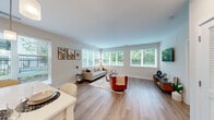 This thoughtfully designed single-floor residence offers 3 bedrooms, 2 bathrooms, and a closet, all connected by a clean, light-filled hallway with light wood-tone flooring that runs throughout the home. The open-concept kitchen and living area serves as the heart of the space, where the kitchen features light wood cabinetry, stainless steel appliances, a white quartz countertop island, subway tile backsplash, and pendant lighting. An adjacent dining area with window access makes the space feel airy and functional. The living room is generously proportioned and framed by large windows on multiple walls that invite sweeping views of mature trees, filling the room with natural light and a sense of connection to the outdoors. The primary bedroom is a comfortable retreat, benefiting from its own access to a well-appointed en-suite bathroom complete with a modern floating vanity, clean white countertops, and a glass-enclosed shower. A second full bathroom, equally refined in its finishes, serves the remaining bedrooms. Each bedroom features large windows with lush exterior views, light-toned flooring, and neutral wall colors that create a calm, inviting atmosphere. The overall design is modern and cohesive, with a bright, neutral palette throughout.