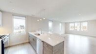 Located in Boston, MA, this modern 2-bedroom, 2-bathroom residence offers a thoughtfully designed single-floor layout with a clean, contemporary aesthetic throughout. Light-toned hardwood flooring flows seamlessly across the open living areas, complemented by neutral wall tones and recessed lighting that create a bright, airy ambiance.

The kitchen is outfitted with stainless steel appliances — including a full-size refrigerator and gas range — alongside wood-grain cabinetry, white quartz countertops, and a window framing city views. The layout allows for efficient use of space while connecting naturally to the living area.

The primary bedroom is generously proportioned, featuring large windows that draw in natural light and overlook the surrounding cityscape. The second bedroom also benefits from its own window and light-filled atmosphere. A dedicated walk-in closet with built-in shelving and hanging systems provides ample storage.

Both bathrooms are finished with care: the primary bath showcases a glass-enclosed shower with large-format marble-look tile, while the second bath includes a full tub-shower combo with classic white subway tile and dark floor tile. An in-unit stacked washer and dryer adds convenience. The overall design is modern, clean, and functional.