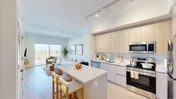 Located at 1715 N Dixie Hwy in Lake Worth Beach, Florida, this thoughtfully designed one-bedroom, one-bathroom residence offers a bright and modern living experience. The open-concept kitchen and living area forms the heart of the home, anchored by a sleek center island with bar seating — ideal for casual dining or entertaining. The kitchen is outfitted with light wood cabinetry extending to the ceiling, stainless steel appliances including a refrigerator, range, microwave, and dishwasher, and clean white countertops. Track lighting overhead enhances the contemporary aesthetic. Light wood-tone flooring flows throughout the space, adding warmth and continuity. The living area is generously proportioned, benefiting from abundant natural light and direct access to a private balcony through sliding glass doors, which frame expansive outdoor views of the surrounding landscape. The bedroom is a serene retreat, featuring a large window that invites natural light and overlooks the treetop scenery. Two closets provide ample storage, complemented by a dedicated pantry and utility room. The bathroom features full tile surround, a soaking tub with shower, and a clean, functional vanity. This well-appointed residence delivers a refined yet comfortable lifestyle in a vibrant South Florida location.