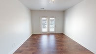 This single-floor, 2-bedroom, 2-bathroom residence offers a thoughtfully designed layout that balances comfort and functionality. The open-concept living area features rich, dark hardwood-style flooring and a ceiling fan, creating a warm and inviting atmosphere. French doors flood the space with natural light and provide direct access to an outdoor area, enhancing the sense of openness.

The kitchen is equipped with dark espresso cabinetry, granite-style countertops, and a full suite of black appliances including a refrigerator, electric range, and over-the-range microwave. A peninsula counter connects the kitchen to the living area, making it ideal for both meal prep and casual dining.

Both bedrooms are carpeted and feature ceiling fans and large windows that bring in ample natural light. The neutral tones throughout provide a clean, versatile backdrop.

The two bathrooms are finished with light tile flooring and dark espresso vanity cabinetry topped with light countertops. Each bathroom includes a tub-shower combination and an oval mirror, maintaining a consistent and cohesive design aesthetic throughout the home.