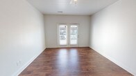 This single-floor, 2-bedroom, 2-bathroom residence offers a thoughtfully designed layout that balances comfort and functionality. The open-concept living area features rich, dark hardwood-style flooring and a ceiling fan, creating a warm and inviting atmosphere. French doors flood the space with natural light and provide direct access to an outdoor area, enhancing the sense of openness.

The kitchen is equipped with dark espresso cabinetry, granite-style countertops, and a full suite of black appliances including a refrigerator, electric range, and over-the-range microwave. A peninsula counter connects the kitchen to the living area, making it ideal for both meal prep and casual dining.

Both bedrooms are carpeted and feature ceiling fans and large windows that bring in ample natural light. The neutral tones throughout provide a clean, versatile backdrop.

The two bathrooms are finished with light tile flooring and dark espresso vanity cabinetry topped with light countertops. Each bathroom includes a tub-shower combination and an oval mirror, maintaining a consistent and cohesive design aesthetic throughout the home.