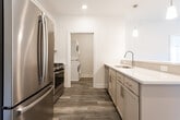 Located at Whitty Road in Toms River, NJ, this thoughtfully designed single-floor residence offers a clean, contemporary aesthetic with high-quality finishes throughout. The open-concept living and dining area is anchored by warm wood-look luxury vinyl plank flooring, recessed lighting, and crisp white walls that create a bright, welcoming atmosphere. The well-appointed kitchen is a standout feature, showcasing soft-tone shaker cabinetry with brushed nickel hardware, gleaming quartz countertops, a subway tile backsplash, and a full suite of stainless steel appliances including a gas range, microwave, and French door refrigerator. A dedicated laundry room provides added convenience, complete with a stacked washer and dryer unit alongside ample cabinetry and counter space. The carpeted bedrooms offer a comfortable retreat, with generous natural light from large windows and ceiling fans for year-round comfort. The walk-in closet features a full wire shelving system, maximizing storage. The primary bathroom impresses with marble-look tile flooring and walls, a glass-enclosed walk-in shower, and a quartz vanity. A second bathroom includes a tiled tub-shower combination and a mirrored medicine cabinet. This residence combines modern design with practical amenities for comfortable everyday living.