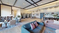 Located at 105 S Main St in Layton, Utah, this expansive amenity center spans a generous single floor designed to accommodate a wide range of social and recreational activities. The open-concept layout is anchored by wide-plank hardwood flooring throughout and a distinctive coffered ceiling with bold dark-trimmed beams that lend an upscale, contemporary character to the space.

The fully equipped kitchen features a large island with seating for multiple guests, dark cabinetry, open shelving with a subway tile backsplash, and stylish pendant lighting — ideal for entertaining. Adjacent to the kitchen, the main gathering area offers multiple lounge seating arrangements, a fireplace, and floor-to-ceiling windows that draw in abundant natural light and provide views of an outdoor patio area.

A dedicated game room includes a pool table, shuffleboard, and arcade machines, while a separate area with glass garage doors opens the space further and adds to its versatile, social atmosphere. A private golf simulator room provides an immersive experience complete with a full-wall projection screen and a putting surface. A sleek conference-style room with built-in AV capabilities rounds out the amenities, offering a more focused environment for meetings or presentations.