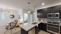 This contemporary apartment showcases a harmonious blend of style and functionality. The heart of the home is a sleek kitchen, boasting dark cabinetry contrasting beautifully with light granite countertops. Stainless steel appliances and a large island with seating complete the culinary space. The open floor plan seamlessly connects the kitchen to a bright living area, adorned with modern furnishings and artistic lighting fixtures.

The bathrooms are generously sized, featuring double vanities with granite countertops, large mirrors, and glass-enclosed showers. Wood-look flooring runs throughout, adding warmth to the crisp white walls. Bedrooms offer ample space and natural light, with one room including a walk-in closet.

A dedicated laundry area with full-sized washer and dryer adds convenience. The apartment's design emphasizes clean lines and a neutral color palette, creating a sophisticated urban oasis. Attention to detail is evident in the carefully chosen artwork, stylish light fixtures, and thoughtful layout that maximizes space and comfort in every room.