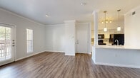 This single-story, 3-bedroom, 2-bathroom home offers a thoughtfully designed layout that maximizes comfort and functionality. The open-concept living and kitchen area serves as the heart of the home, featuring durable wood-look flooring, crown molding, and recessed lighting throughout. The kitchen is equipped with black appliances, white cabinetry, a striking quartz-topped peninsula with pendant lighting, and a tile backsplash — all flowing seamlessly into the living space. A sliding glass door and flanking windows in the living area invite abundant natural light and provide access to the outdoors. The primary bedroom offers a ceiling fan and a spacious walk-in closet with built-in shelving and hanging rods. Each bedroom maintains the consistent wood-look flooring found throughout the home. The bathrooms are finished with white cabinetry, quartz countertops, and a tiled tub-shower combination accented with a decorative mosaic border. Additional conveniences include a dedicated laundry room, a pantry, and three closets for ample storage. A connected hallway efficiently links all rooms, creating a cohesive and practical single-floor living experience.