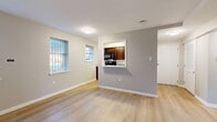 Located at 3314 13th St SE in Washington, DC, this two-bedroom, one-bathroom unit offers a well-organized single-floor layout designed to maximize functionality. The living area is bright and open, featuring light wood-tone flooring and neutral gray walls that create a clean, modern aesthetic. Natural light filters in through double windows dressed with horizontal blinds, lending the space an airy feel.

A distinctive pass-through window connects the living area to the kitchen, offering both visual openness and convenient serving access. The kitchen is equipped with rich dark wood cabinetry, light stone-look countertops, and black appliances including a gas range, over-the-range microwave, and dishwasher — all set on matching light wood flooring.

The primary bedroom is generously proportioned, featuring two windows that invite ample natural light and a double-door closet for storage. A secondary bedroom offers its own window with an exterior view and similarly neutral finishes. Both rooms continue the consistent wood-tone flooring found throughout the unit.

The bathroom is cleanly appointed with white subway tile surrounding a soaking tub and shower, a wood-toned vanity with a white countertop, and a window for natural ventilation. Two hallways connect the rooms efficiently, completing this thoughtfully laid-out Washington, DC residence.