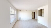 This single-floor, one-bedroom, one-bathroom unit offers a straightforward and efficient layout designed to maximize every square foot. The living area is bright and open, featuring neutral carpet flooring, crisp white walls, and a large window fitted with blinds that allows ample natural light to fill the space. A built-in niche and a pass-through to the kitchen add subtle architectural character to the main living area.

The galley-style kitchen is thoughtfully organized, featuring warm wood-toned cabinetry on both upper and lower sections, light countertops with a stainless steel sink, and tile flooring. White appliances, including a refrigerator and electric range, are included, making the kitchen fully equipped and functional.

The bedroom is a comfortable, carpeted room with its own window offering natural light and views of surrounding greenery. A dedicated closet provides convenient built-in storage. The neutral, clean palette of the bedroom makes it easy to personalize.

The bathroom includes a full tub and shower surround in white, maintaining the clean and minimal aesthetic found throughout the unit. A hallway connects the key areas of the home, providing a logical flow between spaces. Overall, this unit presents a clean, neutral, and functional living environment well-suited for efficient everyday living.
