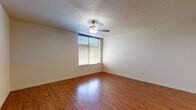 Located in Portland's Northwest District at 1986 NW Pettygrove St, this single-floor residence offers a practical and comfortable layout with consistent design elements throughout. The main living area is generously proportioned, featuring warm hardwood-style flooring that runs throughout the space, adding a welcoming and cohesive feel. A ceiling fan with integrated lighting is centrally mounted beneath a textured ceiling, providing both air circulation and ambient light. A large window fitted with horizontal blinds allows natural light to fill the room while maintaining privacy.

The kitchen is efficiently designed with warm-toned wood cabinetry offering ample upper and lower storage, a double-basin sink, and black appliances including a full-size refrigerator and dishwasher. A recessed ceiling light ensures the workspace is well illuminated. The flooring continues seamlessly from the living area into the kitchen, maintaining visual continuity.

The bathroom features a clean, walk-in shower stall with built-in shelving and a curtain rod, complemented by safety grab bars and neutral tile flooring. The space also includes a dedicated entry area with a closet, providing practical storage upon arrival. Throughout the unit, white walls, clean trim, and recessed lighting contribute to a bright, understated, and move-in-ready atmosphere.