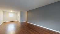 Located at 126 New Britain Ave in Plainville, Connecticut, this single-floor unit offers a practical and clean layout with a cohesive, neutral aesthetic throughout. Rich, dark hardwood flooring runs through the main living areas and bedroom, providing warmth and continuity across the space.

The open living area is finished with cool gray walls and crisp white trim, creating a calm and versatile backdrop. Natural light enters through windows fitted with blinds, and baseboard heating is present throughout, ensuring year-round comfort.

The bedroom is a standout feature, offering ample storage with two side-by-side sliding-door closets that span a full wall. The room also benefits from a dedicated window that brings in natural light and views of the surrounding neighborhood.

The kitchen is equipped with white cabinetry, laminate countertops, a stainless steel sink, an electric range, and a full-size refrigerator. Stone-look tile flooring grounds the space and complements the clean white cabinetry.

The bathroom is neatly finished with white tile wainscoting, stone-look tile flooring, a vanity with storage, a shower-tub combination, and a window that provides natural ventilation and light. The overall space is clean, move-in ready, and well-maintained.