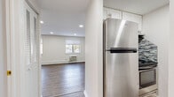Located at 218 Ft Pleasant Ave in Springfield, MA, this single-floor unit has been thoughtfully renovated with contemporary finishes and a cohesive, clean design. Throughout the living areas, light wood-look laminate flooring creates a warm, consistent foundation, complemented by crisp white walls and recessed lighting that keeps the space feeling bright and open. Baseboard heating runs along the perimeter of the main rooms, and a wall-mounted air conditioning unit provides additional climate control.

The spacious living area features two windows that invite natural light and provide views of the surrounding neighborhood, enhancing the open, airy feel of the room. The layout flows naturally toward the kitchen, which is outfitted with white cabinetry, a stainless steel refrigerator, and a mosaic tile backsplash that adds a subtle decorative touch.

A dedicated sleeping area offers a closet with louvered doors and connects to a hallway leading to the bathroom. The bathroom is well-appointed with patterned mosaic tile flooring, white subway tile walls, a glass-enclosed shower, a white vanity with a dark stone countertop, a vessel sink, and brushed gold fixtures that lend a refined finishing touch to the space.