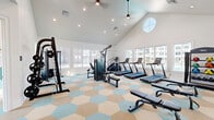 Located in Eagle, Idaho, this single-floor fitness center offers a thoughtfully designed space for health and wellness. The centerpiece is a generously sized exercise room crowned by soaring vaulted ceilings and a distinctive circular window that floods the space with natural light. Recessed lighting and a pendant ceiling fan complement the bright, airy atmosphere. Large windows line the walls, providing views of the surrounding neighborhood and further enhancing the open feel. The exercise room is outfitted with a comprehensive selection of equipment, including multiple treadmills, cable and multi-function weight machines, a squat rack, adjustable benches, and a full dumbbell rack with medicine balls. A mirrored wall section supports strength and form training. The eye-catching hexagonal patterned flooring in soft blue, tan, and beige tones adds a modern, welcoming aesthetic throughout. A dedicated play area — bright and cheerfully decorated with a teal accent wall mural, framed artwork, and a children's table and chairs — offers a convenient space for young visitors. The facility also includes a private office and an entry area with clearly posted fitness center guidelines, all accessible via a glass-paneled exterior door.