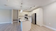 Located at 2116 Pleasant Road in Fort Mill, SC, this thoughtfully designed single-floor residence offers a cohesive blend of modern finishes and functional layout across a comfortable footprint. Light wood-look flooring flows throughout the main living areas, lending a bright, airy feel to the open-concept space.

The kitchen is a standout feature, showcasing white shaker cabinetry with brushed nickel hardware, stone-look countertops, a classic subway tile backsplash, and a full suite of stainless steel appliances including a range, microwave, and French door refrigerator. A built-in wine cooler adds a refined touch. A central island with a sink and pendant lighting above serves as both a prep area and casual gathering spot, while a track lighting system provides additional illumination.

The living area is generously proportioned with a ceiling fan and windows that invite natural light and outdoor views. The bedroom features plush carpeting, large windows with blinds, and ample wall space. The bathroom is finished with marble-look tile flooring, a vanity with countertop storage, and a glass-enclosed walk-in shower. A dedicated laundry room with side-by-side washer and dryer and overhead wire shelving completes the layout, offering practical everyday convenience.