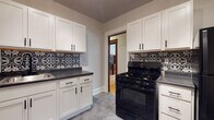 Located at 3059 N Maryland Ave in Milwaukee's vibrant East Side neighborhood, this single-floor unit blends classic architectural character with thoughtful modern updates. Hardwood flooring flows throughout the living areas and bedrooms, complemented by rich, dark wood trim that frames doorways and windows, adding a timeless warmth to the interior.

The living room serves as a standout space, featuring a decorative fireplace with a clean white surround, dark mantel, and a patterned tile hearth, along with crown molding that adds elegance to the room. The bedrooms are bright and well-proportioned, with multiple windows allowing generous natural light, ceiling fans, and classic cast-iron radiators providing efficient heating.

The kitchen has been updated with crisp white shaker cabinetry, dark granite-style countertops, a black gas range, and a bold black-and-white patterned tile backsplash that serves as a striking design focal point. The neutral tile flooring grounds the space with a clean, contemporary feel.

The bathroom retains its charming character with a classic penny-tile floor featuring a floral motif, a full soaking tub with subway tile surround, and a natural wood door that echoes the period detailing found throughout. The overall ambiance of this home balances historic Milwaukee charm with functional, updated living spaces.