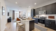 This thoughtfully designed 2-bedroom, 2-bathroom residence in Manor, TX features a contemporary aesthetic throughout its single-floor layout. Light wood-style flooring flows seamlessly across the living areas, creating a warm and cohesive atmosphere.

The open-concept kitchen is a standout feature, showcasing dark navy shaker-style cabinetry, granite countertops, a subway tile backsplash, stainless steel appliances, and a central island with bar seating — ideal for both cooking and casual dining. The kitchen opens directly to the living room, which is bathed in natural light from large French doors leading to an outdoor balcony, framed by floor-to-ceiling drape panels.

Both bedrooms are comfortably sized, featuring large windows that invite natural light, ceiling fans, and easy access to dedicated closets outfitted with built-in shelving and gold-toned hanging rods. The primary bathroom features a dual-sink vanity with dark cabinetry and granite counters, and a glass-enclosed walk-in shower with tile surround. The secondary bathroom mirrors the refined style with a similar vanity and a full soaking tub with shower.

The overall ambiance is clean, modern, and welcoming — a well-balanced residence designed for both comfort and style in the heart of Manor, TX.