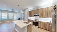Located at 1817 Hickory St in Dallas, TX, this thoughtfully designed 2-bedroom, 4-bathroom home offers a modern aesthetic with high-quality finishes throughout its single-floor layout. The open-concept kitchen and living area serves as the heart of the home, featuring wood-grain cabinetry, stainless steel appliances — including a range, microwave, and French door refrigerator — and a striking quartz-topped island with an undermount sink and pendant lighting. Light hardwood flooring flows seamlessly through the living spaces, complementing the cool gray wall tones. The living room is highlighted by a sleek wall-mounted electric fireplace, recessed lighting, a ceiling fan, and direct outdoor access through a glass door flanked by large windows that invite abundant natural light. The bedrooms are well-proportioned, each offering hardwood floors, natural light, and access to their own bathrooms. The bathrooms are finished with warm wood vanities, white quartz countertops, large mirrors, and walk-in glass-enclosed showers adorned with bold hexagonal tile. The closets feature built-in shelving and rod systems for organized storage. The overall ambiance is clean, contemporary, and move-in ready.