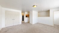 Located at 721 S Mountain Rd in Dillsburg, PA, this 2-bedroom, 1-bathroom home offers a straightforward and functional layout across a single floor. The living area is carpeted and open, with clean white walls and a ceiling light fixture that keeps the space bright. A pass-through opening connects the living area to the galley-style kitchen, which features warm oak cabinetry lining both walls, dark laminate countertops, a double-basin stainless steel sink, and black appliances including a refrigerator, range, and dishwasher. The classic checkered tile flooring adds a timeless touch to the kitchen. Both bedrooms are carpeted and finished with neutral tones, each equipped with a closet featuring a built-in rod and shelf. Windows in the bedrooms allow natural light and offer views of surrounding greenery. The full bathroom includes a wooden vanity with a light countertop, a toilet, and grab bars, with earthy stone-look tile flooring adding a durable, practical finish. A carpeted staircase with a wood handrail provides access between levels. Overall, the home presents a clean, no-frills interior well-suited for comfortable everyday living.