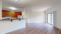 Located at 9030 Lorton Station Blvd, Unit 319, in Lorton, Virginia, this one-bedroom unit offers a thoughtfully designed single-floor layout with a clean, neutral aesthetic throughout. Warm hardwood-style flooring flows consistently across all living areas, complementing the crisp white walls and crown molding detail found in the main living space.

The combined kitchen and living room serves as the heart of the unit. The kitchen is equipped with rich, warm-toned cabinetry featuring arched door details, dark countertops, and a full suite of stainless steel appliances including a refrigerator with water dispenser, a stove, and an over-the-range microwave. A peninsula with an overhanging countertop provides seating and separates the kitchen from the open living area.

The spacious primary bedroom is a standout feature, offering generous room, a ceiling fan with lighting, and a large window that brings in natural light with views of surrounding greenery. A sliding glass door provides direct outdoor access. The bedroom also includes a double closet and connects to an en-suite bathroom with a soaking tub. An additional door within the bedroom offers further storage or utility access, adding to the practical layout of this well-appointed unit.