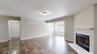 This single-floor, one-bedroom, one-bathroom residence offers a thoughtfully designed layout across a comfortable footprint. The living room serves as the centerpiece of the home, featuring rich wood-look flooring, neutral gray walls, and a classic white-mantled fireplace that adds warmth and character. Large windows flood the space with natural light and provide pleasant outdoor views, enhancing the open, airy feel of the room.

Adjacent to the living room, the dining area is defined by a stylish pendant light fixture and continues the same durable wood-look flooring, creating a seamless flow throughout the common areas. A pass-through window connects the dining space to the kitchen, which is designed in a galley style with white cabinetry, granite-look countertops, a decorative tile backsplash, and black appliances including a gas range, refrigerator, and dishwasher.

The bedroom offers a cozy retreat with plush carpeting, a bright window overlooking greenery, and convenient access to both a dedicated closet with built-in shelving and a full bathroom. The bathroom is clean and functional, featuring a tiled tub-shower combination. A hallway connects the private and shared areas of the home efficiently, completing the practical and cohesive floor plan.