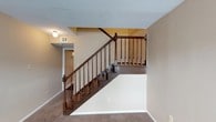 Located at 5201 Monaco Dr in Pascagoula, Mississippi, this two-story home offers a well-organized layout spread across two distinct levels. The interior is finished with neutral, warm-toned walls and wall-to-wall carpeting that lends a comfortable, understated feel throughout the space. A central staircase serves as a defining architectural feature, showcasing rich dark wood railings with turned balusters and decorative newel posts that add a classic, traditional character to the home. The staircase connects both floors in a visually prominent and accessible way. The textured ceiling adds depth and dimension to the interior, while recessed ventilation and flush-mount lighting fixtures ensure practical comfort. A hallway visible from the staircase area suggests well-defined circulation paths that connect the various rooms of the home. The overall ambiance is clean, calm, and move-in ready, with a traditional design sensibility that balances functionality with classic detailing. The two-floor configuration provides natural separation between living and private spaces, making this home suitable for a variety of lifestyle needs.