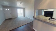 This single-story, 2-bedroom, 2-bathroom residence offers a practical and comfortable layout across a well-utilized footprint. The open living area combines dark hardwood-style flooring with plush carpeting, creating a clear visual distinction between the main entry zone and the carpeted lounge space. A sliding glass door fitted with vertical blinds allows natural light to fill the room while providing outdoor access. A ceiling fan overhead adds both function and casual style.

The kitchen is a standout feature, equipped with dark espresso cabinetry, granite-style countertops, a subway tile backsplash, a double stainless steel sink, and a black electric range. A pass-through window connects the kitchen to the living area, enhancing the open feel.

Both bedrooms are generously proportioned, each with plush carpeting, ceiling fans with light fixtures, and textured ceilings. One bedroom includes a sliding glass door for added natural light, while the other features a standard window with blinds.

The two bathrooms include granite-style countertops and dark wood-style flooring. One bathroom features a full tub-shower combo with white tile surround and chrome fixtures. The overall ambiance is clean, neutral, and move-in ready.