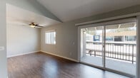 This single-floor residence offers a well-designed layout highlighted by vaulted ceilings that lend an open, airy feel to the living spaces. Wood-style flooring runs throughout the main living and bedroom areas, providing a cohesive and contemporary aesthetic. The living room is generously proportioned, featuring a ceiling fan, a side window that brings in natural light, and sliding glass doors that open onto a private balcony with views of the surrounding neighborhood.

The kitchen is outfitted with crisp white cabinetry, light-toned countertops, and a full suite of stainless steel appliances, including a range, microwave, and dishwasher. A recessed ceiling light provides practical illumination for meal preparation. The layout is efficient and functional, with ample cabinet and counter space.

The bedrooms continue the wood-style flooring and are finished with neutral gray walls, ceiling fans, and windows that allow natural light to filter in. Each room offers a calm, versatile environment suitable for various uses.

The bathrooms are cleanly finished, featuring white vanities with integrated sinks, framed mirrors, and textured walls. One bathroom includes a full tub-shower combination with a curved curtain rod and gold-toned fixtures, complementing the overall neutral palette of the residence.