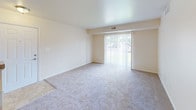 This single-floor unit located at 58830 Van Dyke Rd in Washington, Michigan, offers a well-organized layout designed for comfortable everyday living. The entryway opens into a carpeted foyer with tile accents, providing a welcoming transition into the main living spaces. Adjacent to the entry, a half-wall separates the kitchen, which features a classic galley configuration lined with warm-toned wood cabinetry, laminate countertops, tile flooring, a double-basin stainless steel sink, and white appliances including a refrigerator and range. The living area is generously proportioned, finished with neutral carpet, and anchored by a full-width sliding glass door fitted with vertical blinds that allows ample natural light and outdoor views. The bedrooms are carpeted and well-sized, with one offering direct access to a private bathroom. Two bathrooms are present throughout the unit; one features a walk-in shower with sliding glass doors, chrome hardware, tile surround, a wood vanity with granite-style countertop, and built-in storage shelving. The second bathroom similarly includes tile flooring, a vanity, and closet access. Consistent neutral tones, flush-mount lighting, and clean finishes contribute to a cohesive and functional ambiance throughout the space.