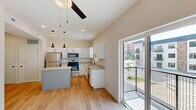 Located at 1729 Nicholasville Rd in Lexington, Kentucky, this well-appointed one-bedroom, one-bathroom unit offers a thoughtfully designed single-floor layout. The open-concept kitchen serves as the heart of the space, showcasing white shaker cabinetry, granite countertops, a center island with additional counter space, and a full suite of stainless steel appliances including a refrigerator, range, microwave, and dishwasher. Stylish pendant lighting hangs above the island, complementing the recessed ceiling lights throughout. Light hardwood-style flooring runs through the kitchen and main living area, creating a clean and cohesive aesthetic. A sliding glass door opens to a private balcony, inviting natural light and outdoor views into the living space, while a ceiling fan adds comfort overhead. A hallway connects the main living area to the private bedroom, which features plush carpeting, a ceiling fan, and a window with serene tree views. The bedroom also provides access to a dedicated closet. Clean white walls, panel-style doors with matte black hardware, and neutral finishes throughout lend the unit a modern, move-in-ready feel. A full bathroom and additional closet storage round out the functional and efficiently arranged floor plan.