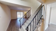 Located at 4122 Laurel Village Dr in Henrico, Virginia, this two-story home offers a well-organized layout designed for comfortable everyday living. The main level features durable hardwood-style flooring throughout the open living area, which is filled with natural light from a large sliding glass door fitted with vertical blinds. A ceiling fan adds functionality to the living space, while a staircase with black metal railings and carpeted treads leads to the upper floor. The kitchen is a standout feature, outfitted with crisp white shaker-style cabinetry, granite-look countertops, a tiled backsplash, a stainless steel sink, and a full suite of stainless steel Whirlpool appliances including a gas range, dishwasher, microwave, and refrigerator, all illuminated by a pendant light above. Upstairs, the bedrooms are carpeted and finished with textured ceilings. The primary bedroom includes a walk-in closet, while another bedroom features mirrored sliding closet doors and a window overlooking the outdoors. An additional bedroom provides a walk-out closet. The bathroom on the upper level is equipped with a tub-shower combination, tile flooring, and a small window for natural ventilation. Throughout, the home presents a clean, neutral palette that provides a versatile and move-in ready environment.