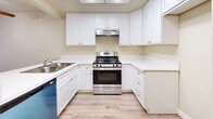 Located at 12801 Rosecrans Ave in Norwalk, CA, this one-bedroom, one-bathroom unit offers a practical and well-organized single-floor layout. The kitchen is a standout feature, equipped with white shaker-style cabinetry extending to the ceiling for ample storage, white countertops, a stainless steel gas range with an overhead ventilation hood, a built-in dishwasher, and a stainless steel sink. A skylight above the kitchen enhances the space with natural light, while a peninsula counter provides additional prep space and an open connection to the rest of the unit. Hardwood-style flooring flows throughout the main living areas and hallway, lending a clean and cohesive aesthetic. The living area benefits from natural light through a window facing outward. The spacious bedroom features the same hardwood-style flooring, neutral warm-toned walls, and a closet with sliding doors offering generous storage. A hallway connects the main areas, with access to a closet and additional storage. The bathroom is outfitted with a full-size soaking tub and shower combo featuring built-in shelving and chrome fixtures. Throughout the unit, neutral beige tones, white trim, and consistent flooring create a unified and move-in-ready environment.