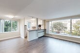 Located at 120 W Third Ave in San Mateo, CA, this 2-bedroom, 1-bathroom residence offers a well-organized single-floor layout designed for comfortable everyday living. The open-concept living and kitchen area forms the heart of the home, bathed in natural light from large picture windows that frame views of the surrounding neighborhood's mature trees and streetscape. Light gray hardwood-style flooring runs throughout, lending a cohesive, modern feel to the space.

The kitchen is thoughtfully appointed with crisp white cabinetry, gray countertops, white subway tile backsplash, and a full suite of stainless steel appliances including a refrigerator, range, microwave, and dishwasher. A breakfast bar peninsula connects the kitchen to the living area, enhancing the open flow.

The generously sized primary bedroom features warm-toned hardwood-style flooring, neutral walls, a closet, and a window overlooking the outdoors. The second bedroom is equally inviting, with its own window and closet. The bathroom is clean and functional, featuring a tub/shower combination with subway tile surround and a frosted window for natural light and privacy. A connecting hallway ties all rooms together efficiently, completing this well-planned San Mateo residence.
