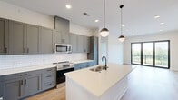 Located at 531 Laketower Drive in Lexington, Kentucky, this well-appointed 2-bedroom, 2-bathroom residence offers a thoughtfully designed single-floor layout with modern finishes throughout. The open-concept living and kitchen area is anchored by a stunning kitchen featuring gray shaker-style cabinetry, stainless steel appliances, a classic white subway tile backsplash, quartz countertops, and a central island with pendant lighting — ideal for both cooking and entertaining. Light hardwood flooring flows throughout the main living areas, complementing the bright, neutral color palette. The living room opens directly to a private balcony through sleek black-framed sliding glass doors, offering elevated views of the surrounding neighborhood and a nearby lake. Both bedrooms are generously sized, carpeted for comfort, and filled with natural light from large windows that frame the serene outdoor scenery. The primary bedroom features a ceiling fan, a walk-in closet with built-in shelving, and a dedicated en-suite bathroom. The bathrooms showcase clean, contemporary design with light tile flooring, white cabinetry, and modern fixtures. Two well-proportioned closets provide ample storage throughout the home. Recessed lighting and a crisp white interior enhance the overall sense of brightness and modern elegance.