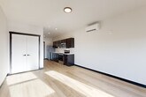 Located at 820 Trail Rd in Sedro-Woolley, WA, this efficiently designed studio unit offers a thoughtful layout that maximizes every square foot of its single-floor plan. The open living area is finished with light-toned hardwood flooring throughout, creating a bright and cohesive feel, while large windows and a glass balcony door flood the space with natural light and frame views of the surrounding landscape.

The kitchen runs along one wall and is well-appointed with dark espresso cabinetry, light countertops, and a full suite of stainless steel appliances, including a refrigerator, electric range, microwave, dishwasher, and sink. Recessed lighting above the kitchen ensures a functional and well-lit workspace. A wall-mounted mini-split HVAC unit provides efficient climate control for the living area.

The bathroom is clean and functional, featuring a combined tub and shower with chrome fixtures, a toilet, and matching light hardwood-style flooring that ties in with the rest of the unit. Storage is accessible via a closet near the entry.

The living area, positioned at the far end of the unit, benefits from direct balcony access through a framed glass door, offering outdoor space and scenic mountain and town views. The overall design is modern, clean, and practical, making efficient use of the available footprint.