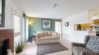 This single-floor residence offers a thoughtfully arranged layout comprising two bedrooms, two bathrooms, a living room, a kitchen, and two closets. The living room serves as the heart of the home, featuring plush carpeting and a distinctive sage green accent wall that adds a touch of character to the otherwise neutral palette. Natural light filters in through large windows dressed with curtains, creating a bright and welcoming atmosphere.

The galley-style kitchen is efficiently designed with warm wood cabinetry, light countertops, tile flooring, and stainless steel appliances including a refrigerator, electric range, and dishwasher — providing all the essentials for everyday cooking.

Both bedrooms are carpeted and well-proportioned. The primary bedroom includes an en-suite vanity area with warm wood cabinetry, a lighted mirror, and access to a dedicated closet. The second bedroom is versatile, accommodating both sleeping and workspace needs, and features a window with natural light. A walk-in style closet with wire shelving provides generous storage.

The bathrooms are finished with wood-toned cabinetry and light countertops; one features a full tub-shower combination. Throughout the residence, a consistent use of neutral tones, carpet, and tile flooring creates a cohesive and functional living environment.