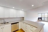Located at 432 Dundas St E in Belleville, Ontario, this thoughtfully updated single-floor residence offers a clean, modern aesthetic throughout. Warm hardwood-style flooring runs continuously across the living spaces, creating a cohesive and inviting atmosphere.

The kitchen is a standout feature, outfitted with crisp white shaker-style cabinetry extending to the ceiling for ample storage, light grey stone countertops, a subtle tile backsplash, and a full suite of stainless steel appliances including a refrigerator, electric range, built-in microwave, and dishwasher. A peninsula provides additional counter space and opens directly to the living area, making the layout ideal for everyday living and entertaining.

The spacious living room is bathed in natural light through large floor-to-ceiling windows and provides direct access to a private balcony, offering pleasant outdoor views. Baseboard heating and a wall-mounted air conditioning unit ensure year-round comfort.

The bedrooms are generously sized, each featuring large windows with roller blinds and hardwood-style flooring. A dedicated hallway connects the sleeping areas and includes closet storage. The unit's neutral palette throughout creates a bright, move-in ready environment. The textured ceiling adds a classic finishing detail consistent across the residence.