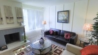 Located at 10025 E Girard Ave in Denver, Colorado, this two-story residential space offers a thoughtfully arranged layout designed for comfortable everyday living. The living room serves as a welcoming centerpiece, featuring carpeted flooring, a textured ceiling, and a large window dressed with vertical blinds that allow for ample natural light to filter into the room. The space accommodates a generous seating arrangement, with room for a sofa and accent chairs gathered around a circular glass coffee table, creating an inviting area for relaxing or entertaining. Decorative wall paneling adds a classic architectural detail to the living area, complemented by warm ambient lighting from a floor lamp. The neutral color palette throughout provides a clean, versatile backdrop that suits a variety of interior styles. Spanning two floors, the home provides a sense of separation between living and private spaces, offering both functionality and privacy. The overall ambiance is calm and residential, with a layout that balances open communal areas with the practical needs of daily life. This Denver property combines classic design elements with a comfortable, livable atmosphere.
