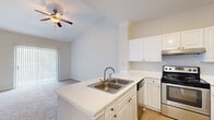 Located at 4807 Pin Oak Park in Houston, TX, this one-bedroom, one-bathroom residence delivers a thoughtfully organized single-floor layout. The open-concept kitchen serves as the heart of the home, featuring a peninsula with a double stainless steel sink and white quartz-style countertops, crisp white cabinetry, stainless steel appliances including a refrigerator and range, and hardwood-style flooring that transitions seamlessly into the living area. The living room impresses with soaring vaulted ceilings, a ceiling fan, and a sliding glass door fitted with vertical blinds that fills the space with natural light and provides access to an outdoor area. The generously sized bedroom features plush carpeting, vaulted ceilings, a ceiling fan, crown molding, and a walk-in closet with built-in shelving. A window with lush outdoor views adds a tranquil touch. The full bathroom is clean and functional, with a tiled tub-shower combo, a single vanity with white cabinetry, light wood-style flooring, and a large mirror. Throughout the residence, a neutral color palette and consistent finishes create a cohesive, bright, and inviting ambiance.