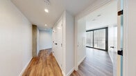 Located at 707 Terry Ave in Seattle's First Hill neighborhood, this modern one-bedroom, one-bathroom unit offers a thoughtfully designed layout across a single floor. Warm hardwood-style flooring flows throughout, complementing the clean, contemporary aesthetic defined by crisp white walls and recessed lighting.

The open-concept living area is anchored by floor-to-ceiling sliding glass doors that frame sweeping views of the Seattle skyline, flooding the space with natural light. An exposed concrete column adds an industrial accent, balancing the warmth of the wood floors. The kitchen is outfitted with white flat-front cabinetry, stainless steel appliances including a refrigerator, range, and microwave, and a stainless steel backsplash for a polished, modern finish.

The bedroom features a sliding closet door and its own set of large floor-to-ceiling windows with perforated screens, offering both light and privacy. A hallway with built-in storage connects the main living spaces.

The bathroom is a standout, featuring dual vessel sinks on a sleek white vanity, a full soaking tub, dramatic floor-to-ceiling dark tile surround, and terrazzo-style flooring — a striking contrast of light and dark finishes that elevates the overall design of the unit.