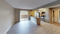 This single-floor residence offers a thoughtfully designed layout that balances comfort and functionality. The open-concept living and kitchen area serves as the heart of the home, featuring light wood-look flooring, neutral taupe and gray walls, and a textured ceiling. Large sliding glass doors flood the living space with natural light while providing direct access to a private balcony with outdoor views.

The kitchen is well-equipped with stainless steel appliances, including a refrigerator, electric range, and over-the-range microwave. Gray cabinetry with brushed nickel hardware pairs elegantly with granite-style countertops, and a peninsula with a built-in sink offers additional workspace and casual seating potential.

A spacious secondary area with wood-look flooring and granite-topped cabinetry provides flexible utility space. The carpeted bedroom offers a calm, comfortable retreat with a window overlooking greenery, delivering a quiet connection to the outdoors.

The bathroom is clean and modern, finished with large-format tile flooring, a granite-topped vanity with gray cabinetry, a wide mirror, and a full tub-shower combination. Throughout the residence, consistent finishes and a neutral color palette create a cohesive, move-in-ready environment suited to a variety of lifestyles.