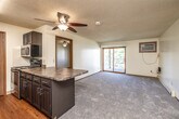 This single-floor unit offers a practical and well-organized layout across two bedrooms and two bathrooms. The open-concept living and kitchen area forms the heart of the space, with the kitchen featuring dark cabinetry, granite-style countertops, stainless steel appliances including a refrigerator, range, microwave, and dishwasher, and durable hardwood-style flooring. A peninsula counter provides a natural division between the kitchen and the carpeted living area, which is illuminated by a ceiling fan and brightened by a sliding glass door leading to a private balcony with outdoor views.

Each bedroom is carpeted and equipped with a ceiling fan, offering a comfortable and quiet retreat. One bedroom includes dual closets with built-in shelving, providing generous storage. Both bedrooms receive natural light from windows or sliding doors.

The two bathrooms are finished with tile flooring and dark vanity cabinetry topped with granite-style counters. One bathroom features a tub-shower combination with sliding glass doors, while the second offers a standalone shower stall. Textured ceilings are consistent throughout the unit, contributing to its cohesive, residential character.