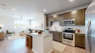 This thoughtfully designed 1-bedroom, 1-bathroom residence offers a functional and stylish layout across a single floor. A welcoming entryway corridor, accented by louvered doors and contemporary artwork, leads into the heart of the home. The open-concept kitchen is a standout feature, equipped with stainless steel appliances including a range, microwave, dishwasher, and French door refrigerator. Rich dark-toned cabinetry, a classic white subway tile backsplash, and a granite-topped center island with bar seating create an ideal space for both cooking and casual dining. The kitchen flows seamlessly into the bright living room, which benefits from multiple windows, an outdoor view, and a ceiling fan overhead — all complemented by light wood-tone flooring throughout. The bedroom is a comfortable, well-proportioned retreat featuring a ceiling fan, a window with natural light, and clean neutral walls. The bathroom mirrors the kitchen's design aesthetic with a dark wood vanity, granite countertop, a large mirror, and a tiled shower-tub combination. Consistent wood-look flooring and a neutral color palette unify the space, lending it a cohesive, modern feel.
