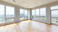 Located on University Avenue SE in Minneapolis, this well-appointed 2-bedroom, 4-bathroom residence offers a generous single-floor layout designed for comfortable urban living. The open-concept living, dining, and kitchen area is anchored by warm hardwood floors and large floor-to-ceiling windows that frame sweeping views of the Minneapolis skyline and surrounding cityscape, flooding the space with natural light. Two stylish globe chandeliers illuminate the dining area, adding a refined touch to the airy atmosphere.

The gourmet kitchen is a standout feature, showcasing rich dark wood cabinetry, quartz countertops, a tile backsplash, stainless steel appliances including a double wall oven and range hood, and a large center island ideal for cooking and entertaining. A marble-surround fireplace adds warmth and elegance to the living area.

The spacious primary bedroom features plush carpeting and direct access to a luxurious en-suite bathroom finished in striking marble tile, complete with a walk-in glass shower and wood-toned vanity. A generously sized walk-in closet with built-in shelving provides ample storage. The additional bedroom is equally well-sized with soft carpet and easy access to the hallway. A dedicated laundry room with a stacked washer and dryer adds everyday convenience.