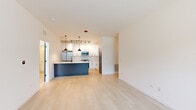 This thoughtfully designed 2-bedroom, 2-bathroom residence in Naperville, IL offers a clean, modern aesthetic throughout. Light-toned hardwood-style flooring flows seamlessly across the entire single-floor layout, creating a cohesive and airy atmosphere. The open-concept living and kitchen area serves as the heart of the home, where a striking navy blue island anchors the kitchen, complemented by crisp white shaker cabinetry, marble-look countertops, stainless steel appliances, and bold matte black pendant lighting and hardware. The living area is bright and spacious, with natural light filtering in from large windows. A connecting hallway with flush lighting leads to both bedrooms, each featuring generous windows with neighborhood views and light wood flooring. The primary bedroom includes a well-organized walk-in closet with built-in shelving and hanging systems. Both bathrooms are finished with clean, contemporary details — one featuring a soaking tub with white subway tile surround and matte black fixtures. A dedicated in-unit laundry area with a full-size washer and dryer adds everyday convenience. The overall ambiance is modern, bright, and move-in ready.