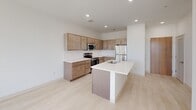 Unit #305 at 106 S Buchanan Street in Spring Lake, Michigan, is a thoughtfully designed one-bedroom, one-bathroom apartment spanning 530 square feet of single-floor living space. The open-concept layout connects the kitchen and living area seamlessly, creating an efficient and airy feel throughout. The kitchen is a standout feature, equipped with warm-toned flat-panel cabinetry, a white quartz countertop island with an undermount sink, stainless steel appliances including a range, microwave, and refrigerator, and a classic white subway tile backsplash. Light luxury vinyl plank flooring flows consistently throughout the unit, complementing the clean, contemporary aesthetic. The bedroom measures 140 square feet and features sliding panel closet doors and crisp white walls, offering a calm, minimalist retreat. Two generously sized windows in the living area flood the space with natural light and provide views of the surrounding Spring Lake streetscape and skyline. The full bathroom includes a tub-shower combination with a curved curtain rod, light-toned finishes, and a vanity. Recessed lighting and neutral tones throughout the unit contribute to a bright, modern atmosphere, making this apartment a practical and stylish home in a charming Michigan lakeside community.