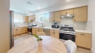 Located at 1165 West 37th Place in Los Angeles, this thoughtfully designed single-story home offers four bedrooms and three bathrooms across a well-organized floor plan. Light-toned hardwood flooring flows consistently throughout, lending warmth and visual continuity to every room.

The kitchen is a standout feature, equipped with dual stainless steel gas ranges, a dishwasher, a stainless steel refrigerator, and light wood cabinetry paired with clean white countertops. A window above the sink fills the space with natural light, and the open layout connects seamlessly to the dining area.

The living area provides a welcoming communal space, while a secondary kitchenette with its own cabinetry and sink offers added versatility. The bedrooms are bright and well-proportioned, with large windows framing outdoor views of the surrounding neighborhood. The spacious primary bedroom includes built-in floor-to-ceiling cabinetry for ample storage. All bedrooms feature recessed lighting and a clean, minimal aesthetic.

Each of the three bathrooms is finished with large-format marble-look tile in the walk-in showers, hexagonal mosaic tile floors, matte black fixtures, and glass enclosures, creating a sleek, modern feel. The overall ambiance is fresh, contemporary, and move-in ready.