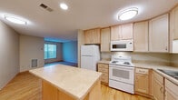 Located at 217 Nebraska Ave W in Saint Paul, Minnesota, this single-floor unit offers a practical and well-organized layout. The combined living, dining, and kitchen area forms the heart of the space, maximizing functionality within a compact footprint. The kitchen is equipped with light maple cabinetry, a built-in microwave, electric range, refrigerator, dishwasher, and a central island with a light countertop that provides additional prep and dining surface. Recessed and flush-mount lighting keeps the area bright and inviting. Hardwood-style flooring flows throughout the main living area and kitchen, adding warmth and visual continuity. The living area is anchored by a large window fitted with vertical blinds, allowing natural light to fill the room and offering a view of the surrounding greenery. The full bathroom features a single-vanity with light cabinetry and stone-tone countertop, a tub-shower combination, and matching hardwood-style flooring for a cohesive feel. Additional storage is available through a dedicated closet, while a utility room adds everyday convenience. The overall aesthetic is clean, neutral, and functional, making efficient use of every square foot.
