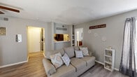 Located at 6675 Old Canton Rd in Ridgeland, Mississippi, this single-floor unit offers a practical and comfortable layout with a warm, neutral color palette throughout. The living area serves as the heart of the space, featuring wood-look flooring, a classic fireplace with a white mantel, and a bright window dressed with floor-length drapes that allow natural light to fill the room. A pass-through window connects the living area to the kitchen, which is outfitted with gray cabinetry, white countertops, and stainless Whirlpool appliances including an electric range and over-the-range microwave. A dedicated dining area provides space for everyday meals. The unit includes multiple bedrooms, each with ceiling fans, wood-look flooring, and ample natural light from windows with blinds. The primary bedroom features a walk-in closet and a dresser-friendly layout, while the secondary bedroom offers a clean, open feel. The bathroom is finished with a full tub-shower combo, vanity with sink, and coordinating wood-look flooring. Consistent gray tones and clean white trim tie the entire space together, creating a cohesive and move-in-ready environment.